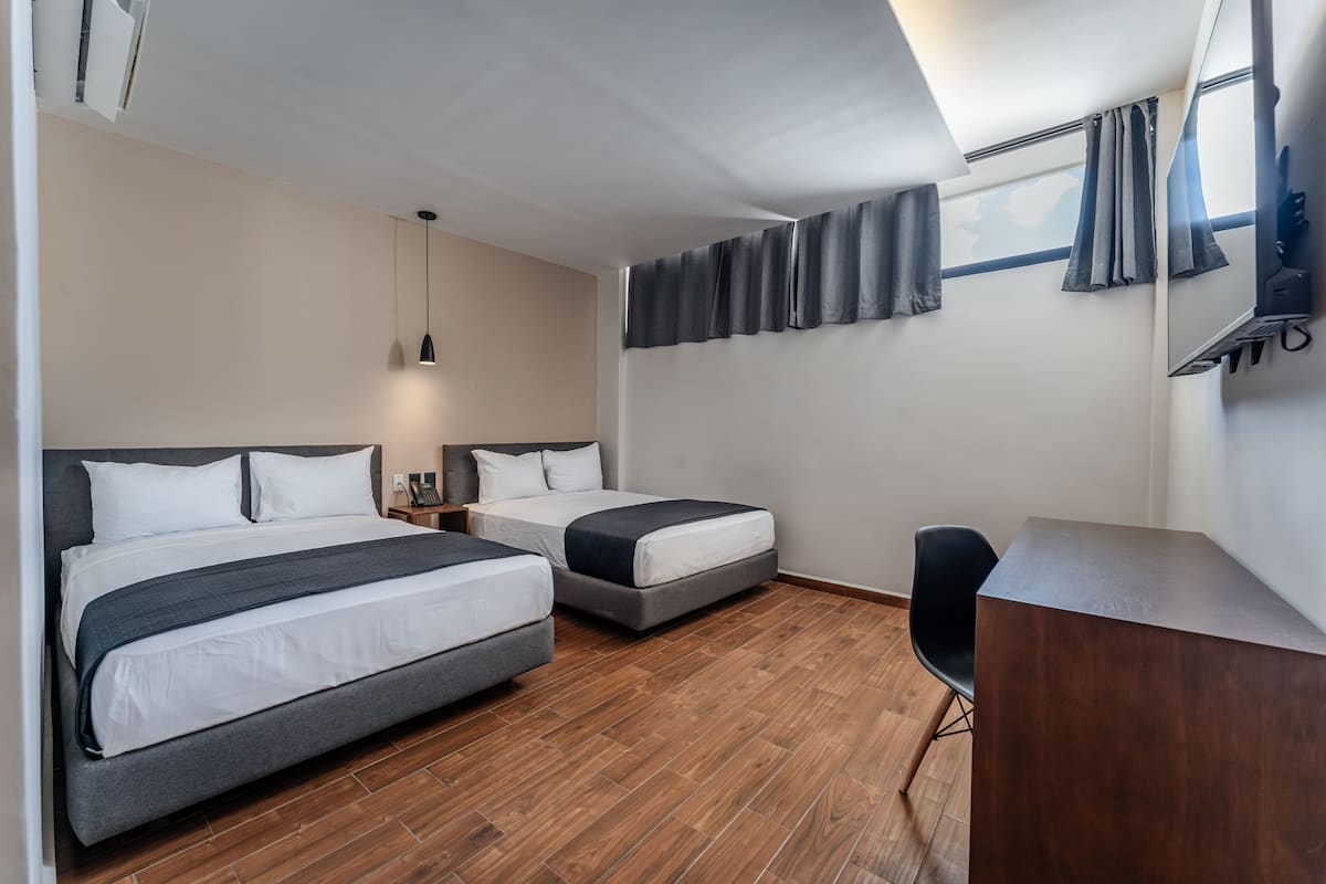 A modern hotel room with two beds, a desk, and a chair.
