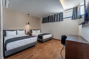 A hotel room with two beds, a desk, and a chair.