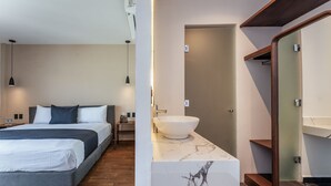 Quarto moderno com cama, mesa de cabeceira e apoio para objetos. Possui banheiro com pia, espelho e chuveiro.