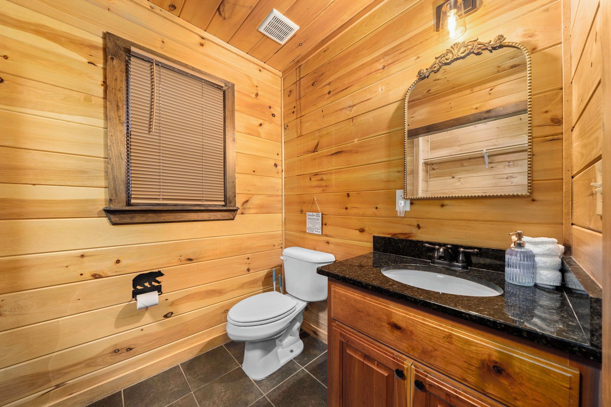 A wooden-paneled bathroom with a toilet, sink, and mirror.