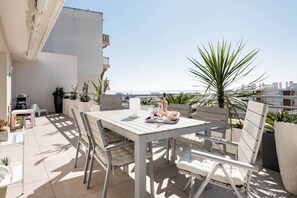 Una terrazza esterna con tavolo e sedie, piante in vaso e vista sul mare.
