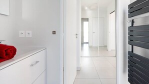 Un baño moderno con un tocador blanco, una toalla roja y un banco negro.