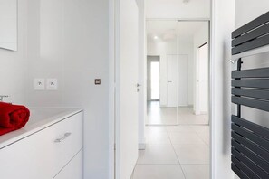 Un bagno moderno con un mobile lavabo bianco, un asciugamano rosso e una panca nera.
