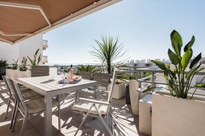 Una terrazza all'aperto con tavolo e sedie, piante in vaso e vista sullo skyline della città.