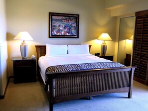 A hotel room with a large bed, two bedside lamps, a painting on the wall, and a mirror on the wall.