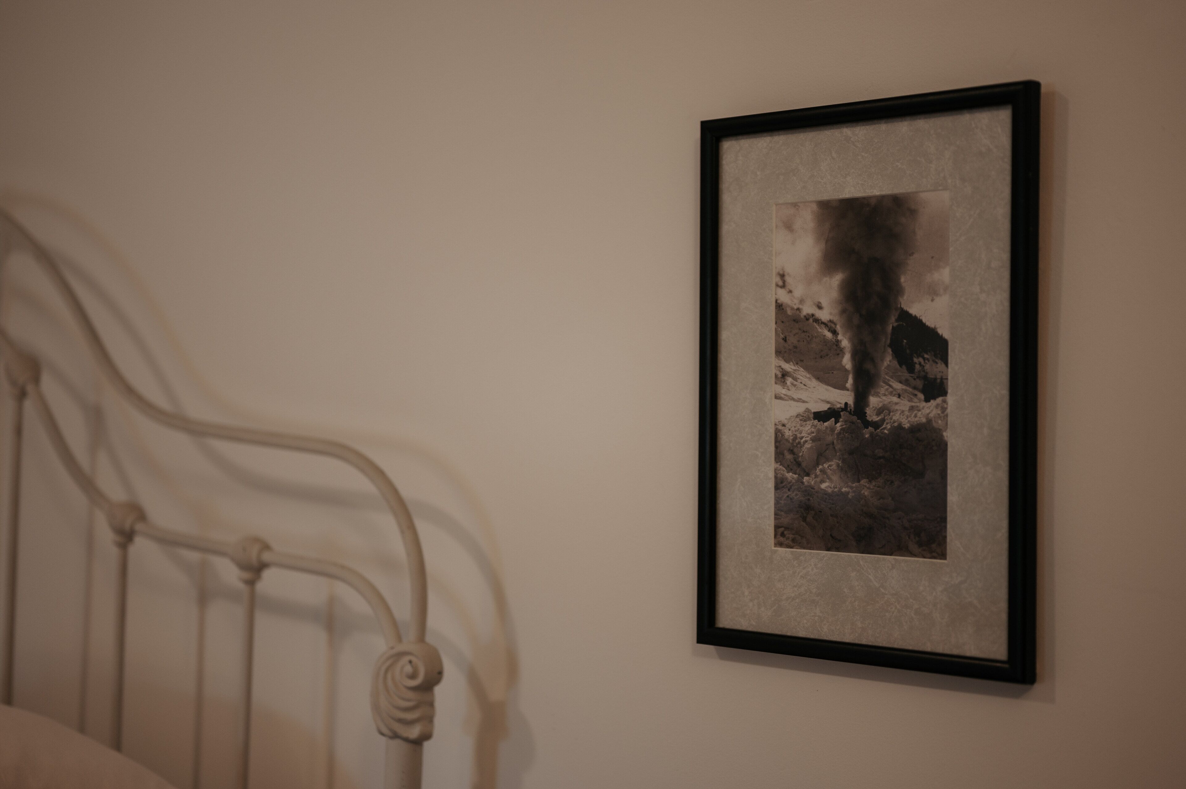 Une photographie encadrée représentant une montagne sur laquelle s’élève une colonne de fumée, accrochée à un mur.