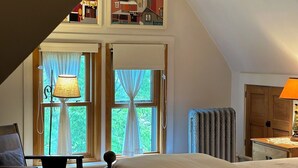 Une chambre à coucher avec un lit, une chaise, une lampe et une vue sur l’extérieur par une fenêtre.