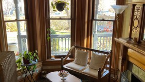 Une pièce agréable et intime, avec un bow-window, un banc rembourré, une petite table et une cheminée.