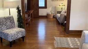 A spacious living room with hardwood floors, a patterned armchair, a sofa, and a coffee table with a book. - A charming craftsman located in the perfect American small town (Saint Lucas)