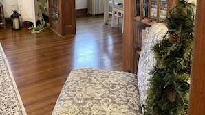 A cozy living room with wooden furniture, a patterned sofa, a small table, and a decorative plant. - A charming craftsman located in the perfect American small town (Saint Lucas)
