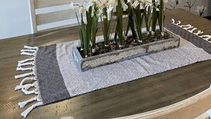 A kitchen with a white refrigerator, a wooden dining table with a black and white patterned runner, and white orchids in a rectangular planter. - A charming craftsman located in the perfect American small town (Saint Lucas)