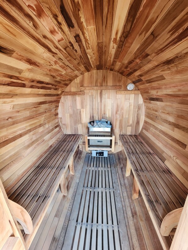 A sauna with wooden walls and benches, a control panel, and a clock on the wall.
