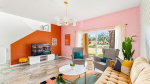 Uma sala de estar moderna com uma televisão grande, assentos confortáveis e vista para o exterior.
