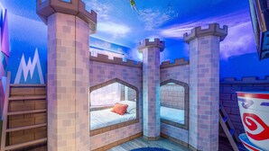 Quarto com tema de castelo, com beliches, escada de madeira e um tapete redondo grande.