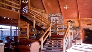 A wooden interior with a staircase, bookshelves, and a stone wall. - Payson | Family Nature Retreat | Pool + Hot Tub | 2BR (Payson)