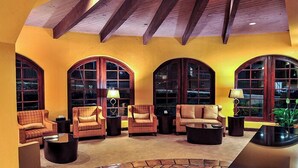 A cozy living room with three armchairs, a coffee table, and a fireplace. Large arched windows provide natural light.