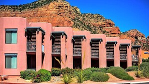 Una hilera de edificios rosados con balcones, con una imponente cadena montañosa de fondo.