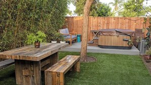 Ein Garten mit einem Holz-Picknicktisch, einer Bank, einem Whirlpool und einem Stuhl.