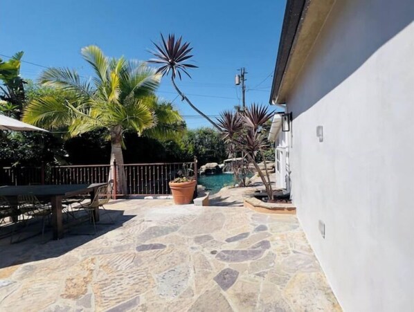A patio area with stone flooring, a pool, and various potted plants.