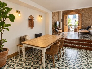 A dining area with a wooden table and chairs, a potted plant, and a patterned floor.