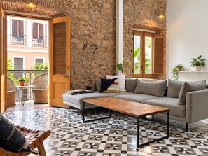 A living room with a stone wall, a sofa, a coffee table, and a patterned floor.