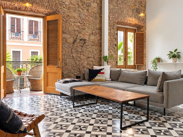 A living room with a stone wall, a sofa, a coffee table, and a patterned floor.