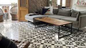 A living room with a stone wall, a patterned floor, a sofa, a coffee table, and a view of the outside. - Newly designed 3BR apartment + Private terrace (Ciudad de Panamá)