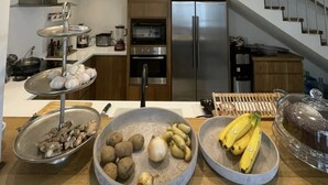 A modern kitchen with a stainless steel refrigerator, a built-in oven, and a two-tiered serving tray with garlic and ginger. - Newly designed 3BR apartment + Private terrace (Ciudad de Panamá)