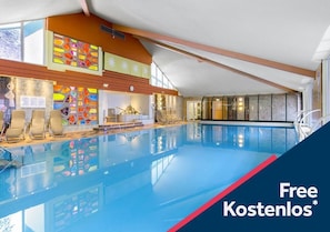 An indoor swimming pool with a modern design, including a sunroof and a colorful stained glass wall.