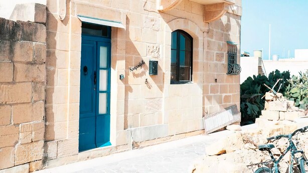Un edificio de piedra con puerta azul y un balcón.