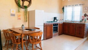 Una cocina compacta con una mesa y sillas, un refrigerador, una estufa y un lavamanos.