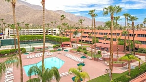 Un resort con piscina, palmeras y montañas al fondo.