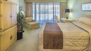 Habitación de hotel con una cama grande, una silla, un escritorio, una lámpara y una planta en maceta.