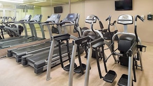 Un gimnasio con varias cintas de correr y elípticas.