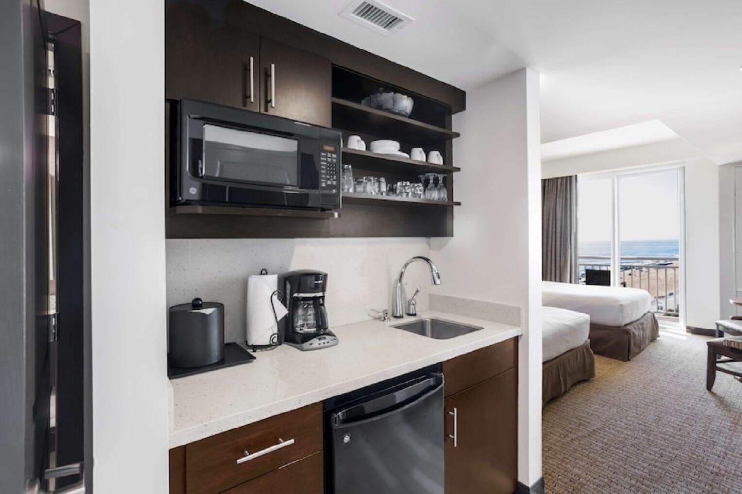 A compact hotel kitchenette with a microwave, coffee maker, and sink.