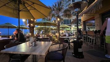 An outdoor dining area with tables and chairs, umbrellas, and a decorative lamp post.