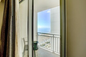 A balcony with a view of the ocean, a chair, and a trash can. - Virginia Beach | Ocean View Balcony Stay | Pool & Beach | Studio (Virginia Beach)