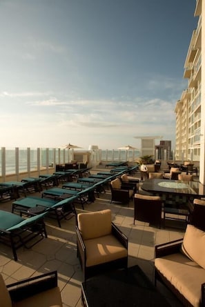 A rooftop lounge with sun loungers, a pool table, and a view of the ocean. - Virginia Beach | Ocean View Balcony Stay | Pool & Beach | Studio (Virginia Beach)