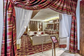 A hotel lobby with a seating area, a reception desk, and a bar. - Virginia Beach | Ocean View Balcony Stay | Pool & Beach | Studio (Virginia Beach)