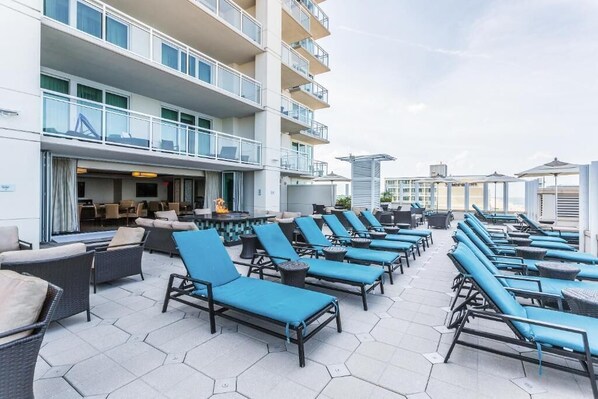 A rooftop lounge with multiple lounge chairs and tables, a bar area, and a view of the city skyline. - Virginia Beach | Ocean View Balcony Stay | Pool & Beach | Studio (Virginia Beach)
