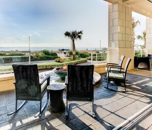 A terrace with wicker chairs, a round table, and a view of the sea.