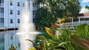 A building with a fountain in front, surrounded by greenery and a clear sky. - Grand Beach - 3 Bedroom Full Mobility - Phase I (Orlando)