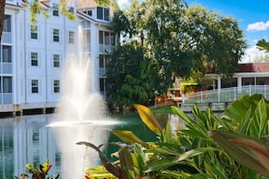 A building with a fountain in front, surrounded by greenery and a clear sky. - Grand Beach - 3 Bedroom Full Mobility - Phase I (Orlando)