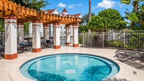 A circular pool with lounge chairs and a covered seating area with a red roof. - Grand Beach - 3 Bedroom Full Mobility - Phase I (Orlando)