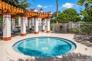 A circular pool with lounge chairs and a covered seating area with a red roof. - Grand Beach - 3 Bedroom Full Mobility - Phase I (Orlando)