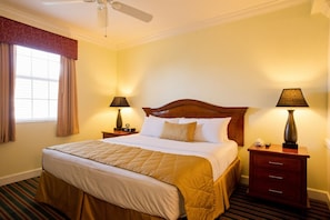 A hotel room with a large bed, two bedside tables, a ceiling fan, and a window with curtains. - Grand Beach - 3 Bedroom Full Mobility - Phase I (Orlando)
