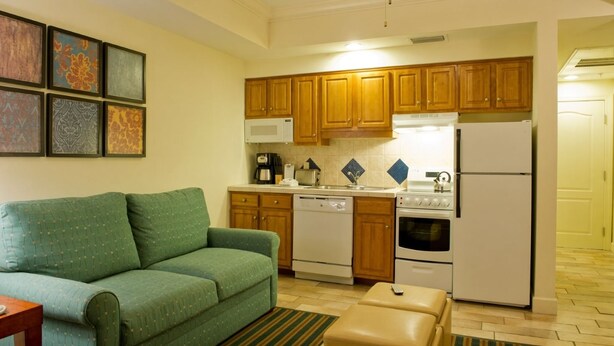 A compact living space with a kitchenette, a green sofa, a coffee table, and a striped rug. - Grand Beach - 3 Bedroom Full Mobility - Phase I (Orlando)