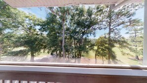 A view through a window with a wooden frame, looking out onto a grassy area with several trees. - Sea Trail Sunset Beach | Golf, Beach & Relaxation | RP 2605 (Sunset Beach)