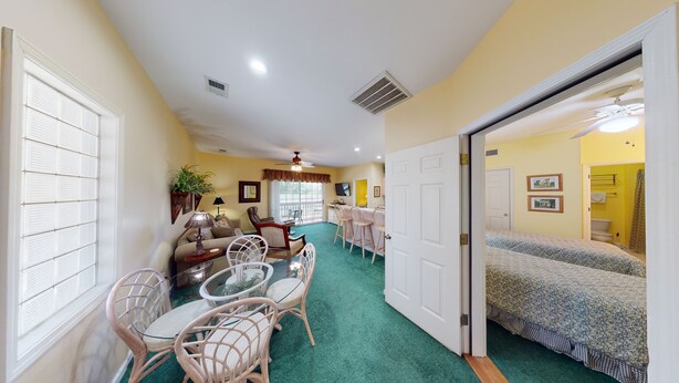 A compact room with a dining area, a sofa, a TV, and a bed. - Sea Trail Sunset Beach | Golf, Beach & Relaxation | RP 2605 (Sunset Beach)