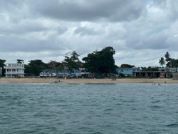 A beach with buildings, trees, and a cloudy sky.